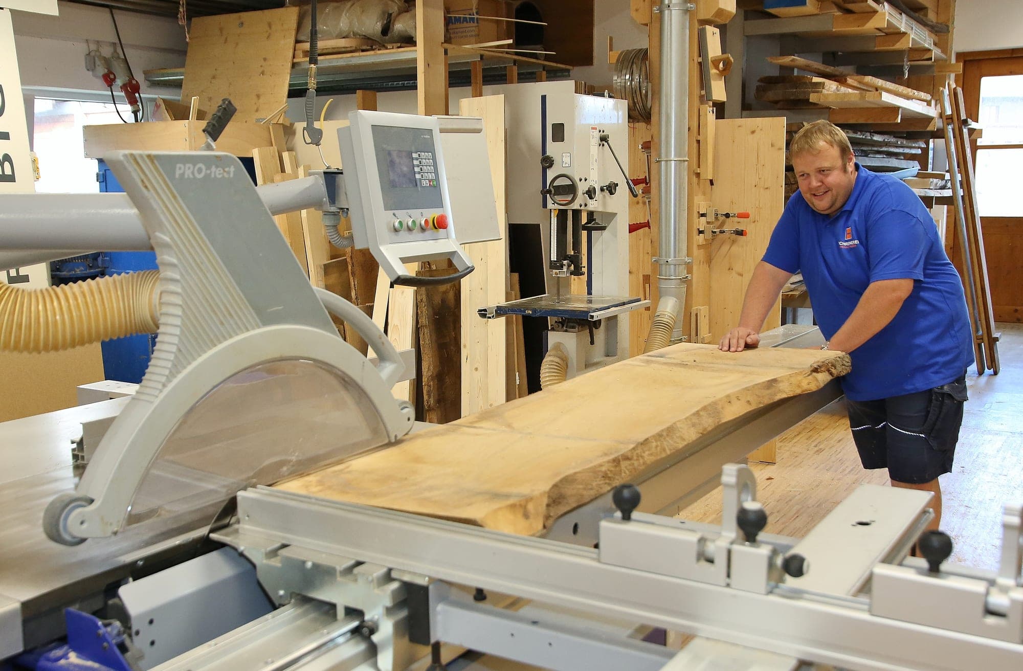 Ein Schreiner schiebt eine Holzbohle über den Tisch der Formatkreissäge